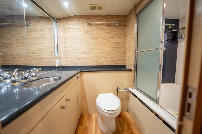 Slide: The Image of Luxurious bathroom in 1998 Hatteras 74 Cockpit Motor Yacht with modern fixtures and wood accents. - 25