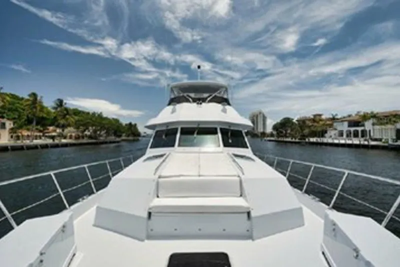 Slide: The Image of 1998 Hatteras 74 Cockpit Motor Yacht cruising on a scenic waterway under a blue sky. - 40