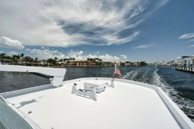 Slide: The Image of 1998 Hatteras 74 Cockpit Motor Yacht cruising on a sunny day with American flag. - 49