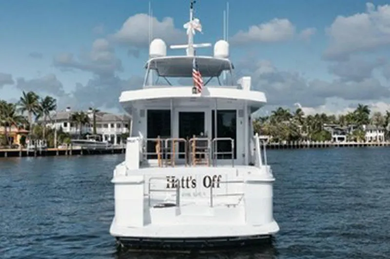 Slide: The Image of 1998 Hatteras 74 Cockpit Motor Yacht on water, rear view, with palm trees in background. - 59