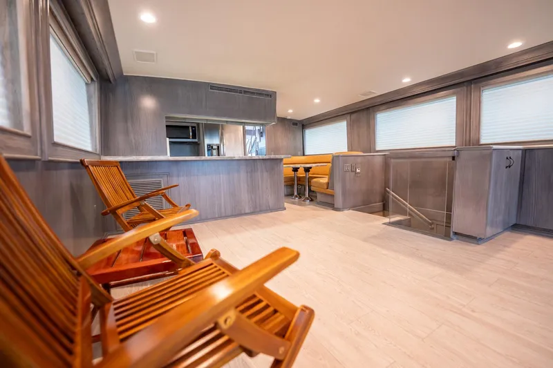 Slide: The Image of Luxurious interior of 1998 Hatteras 74 Cockpit Motor Yacht with wooden chairs and modern decor. - 7