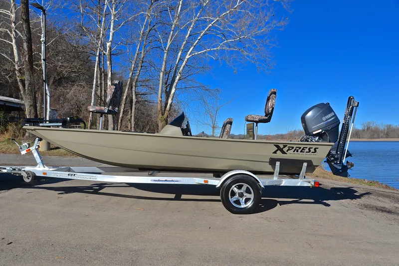 Slide: The Image of 2013 Express Xp170 boat on trailer by lake, clear blue sky background. - 11