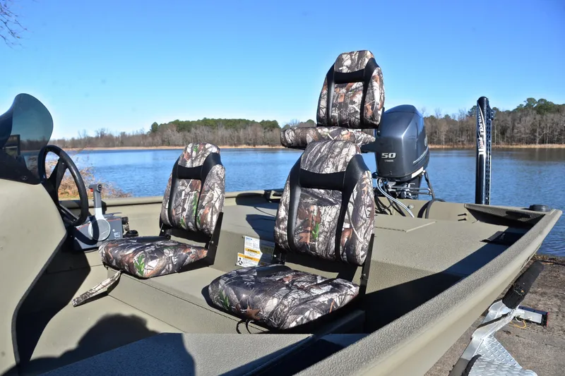 Slide: The Image of 2013 Express Xp170 boat with camo seats, docked by a serene lake. - 18