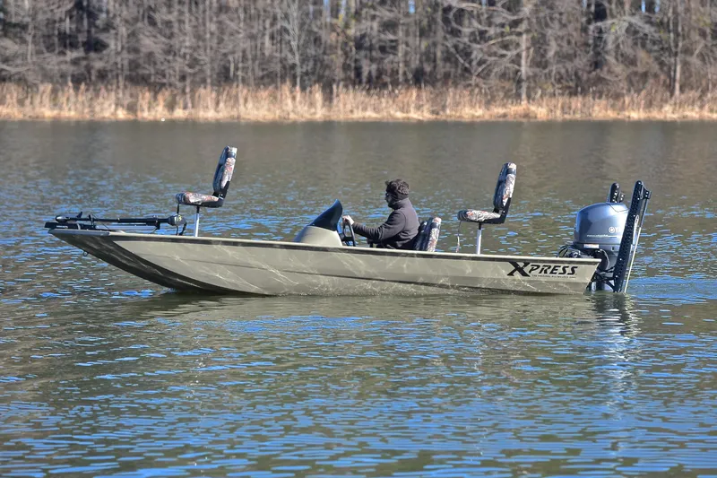 Slide: The Image of 2013 Express Xp170 boat on a calm lake with a person seated, surrounded by trees. - 9