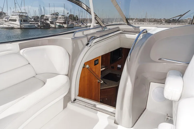 Slide: The Image of 2004 Cruisers Yachts 540 Express interior with white seating and marina view. - 24