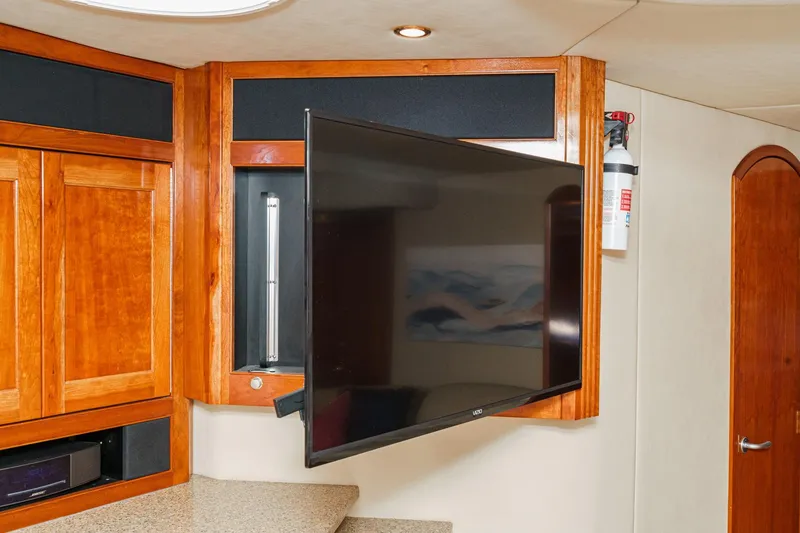 Slide: The Image of 2004 Cruisers Yachts 540 Express interior with mounted TV and wooden cabinetry. - 34