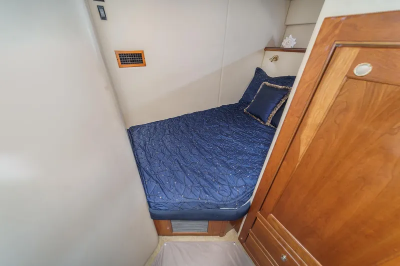 Slide: The Image of 2004 Cruisers Yachts 540 Express cabin with blue bedding and wooden cabinetry. - 54