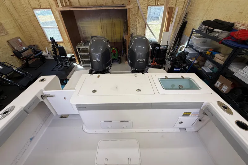 Slide: The Image of 2022 Parker 2501 Center Console boat interior with dual 200 horsepower engines in a workshop. - 33