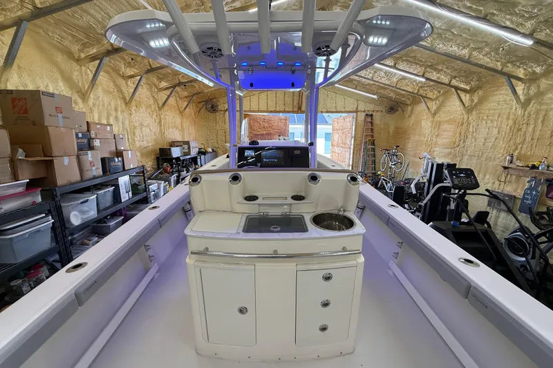 Slide: The Image of 2022 Parker 2501 Center Console boat in a garage with storage boxes and exercise equipment. - 44