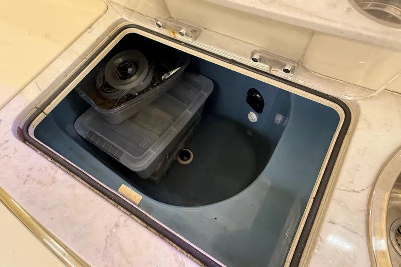 Slide: The Image of Storage compartment on a 2022 Parker 2501 Center Console boat with plastic containers. - 50