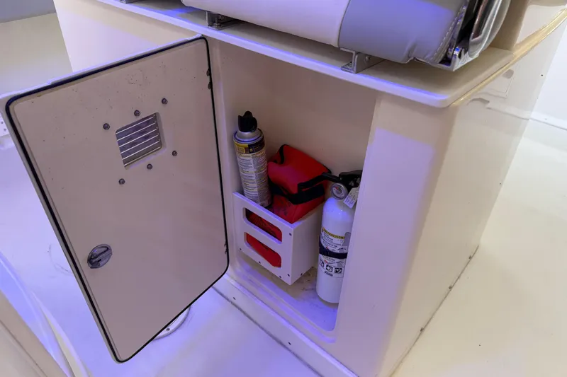 Slide: The Image of Open storage compartment on 2022 Parker 2501 Center Console boat with safety equipment. - 55