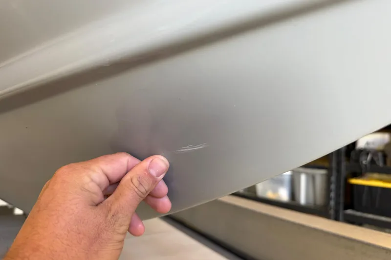 Slide: The Image of Hand inspecting scratch on 2022 Parker 2501 Center Console boat hull. - 7