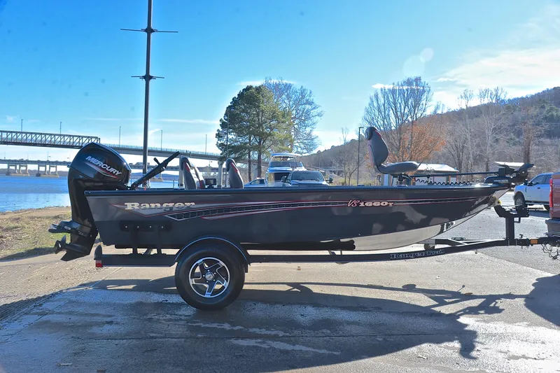 Slide: The Image of 2021 Ranger VS1660 T fishing boat on trailer by riverside, under clear blue sky. - 15