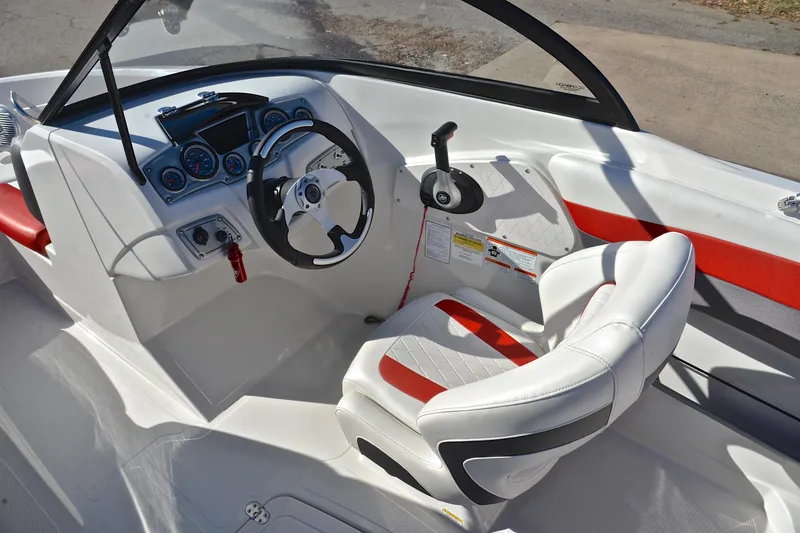 Slide: The Image of 2016 Tahoe 550 TS boat cockpit with steering wheel, gauges, and white-red seating. - 24