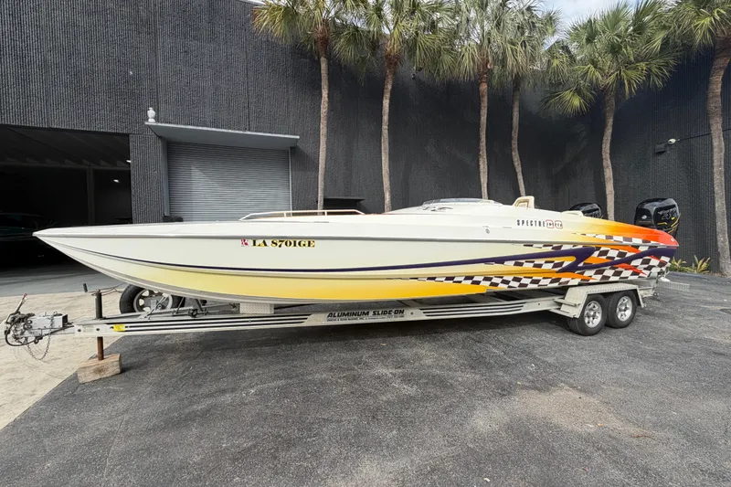 The Image of 2000 Spectre 30 Cat powerboat on trailer, vibrant graphics, parked outdoors. - 0