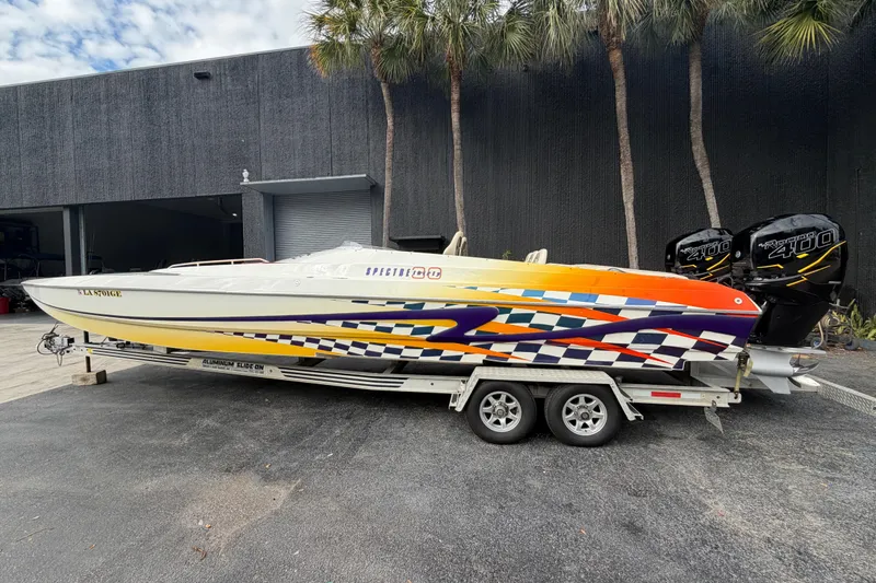 Slide: The Image of 2000 Spectre 30 Cat powerboat with vibrant graphics on a trailer, parked outdoors. - 2