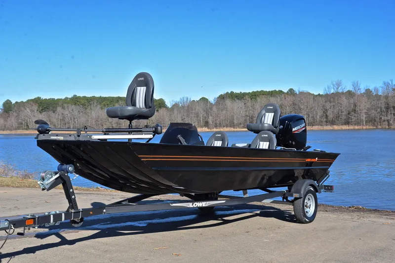 Slide: The Image of 2021 Lowe Legacy boat on trailer by a lake, clear blue sky. - 8