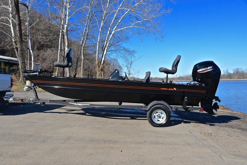 Slide: The Image of 2021 Lowe Legacy boat on trailer by riverside, featuring Mercury outboard motor. - 9