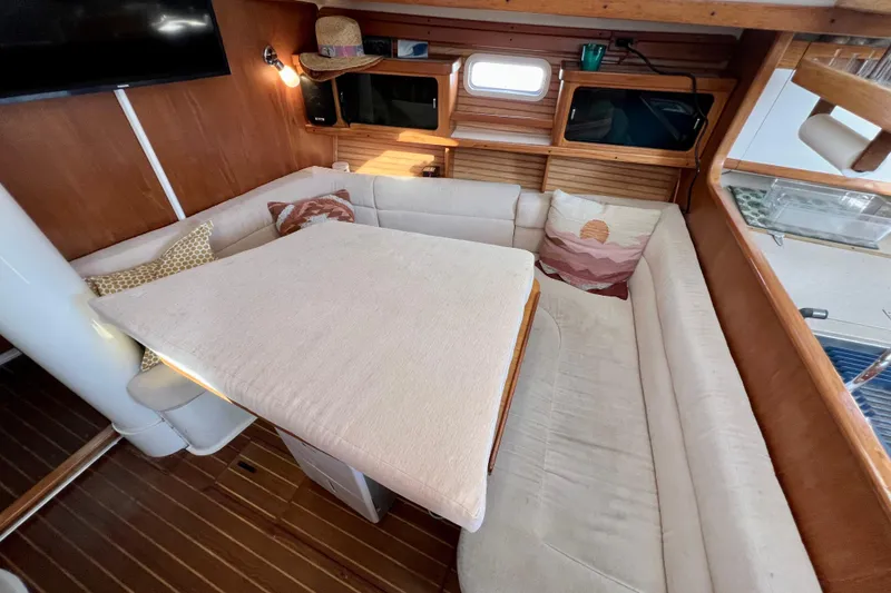 Slide: The Image of Cozy interior of a 1996 Catalina 400 sailboat with cushioned seating and wooden accents. - 52