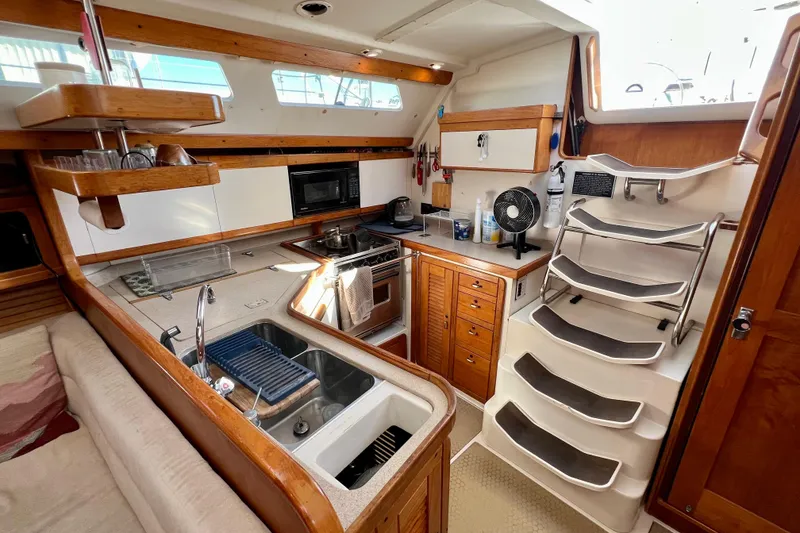 Slide: The Image of Interior of a 1996 Catalina 400 sailboat kitchen with modern amenities and wooden cabinetry. - 56