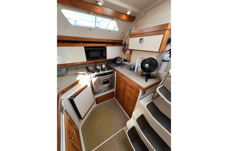 Slide: The Image of 1996 Catalina 400 yacht kitchen with stove, microwave, and wooden cabinetry. - 58