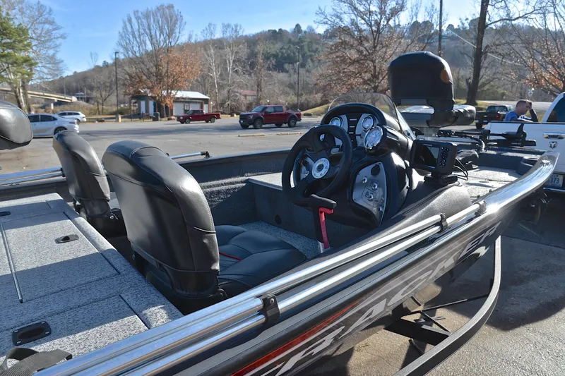 Slide: The Image of 2022 Bass Tracker 175 TF boat interior with steering wheel and seats in a parking lot. - 19