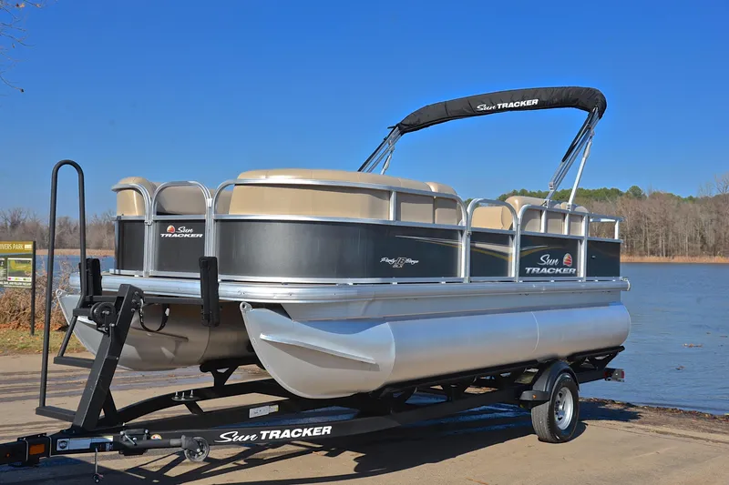 Slide: The Image of 2025 Sun Tracker Party Barge 18 DLX pontoon boat on trailer by a lake. - 10