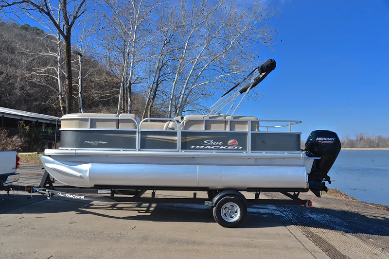 Slide: The Image of 2025 Sun Tracker Party Barge 18 DLX pontoon boat on trailer by a lake. - 11