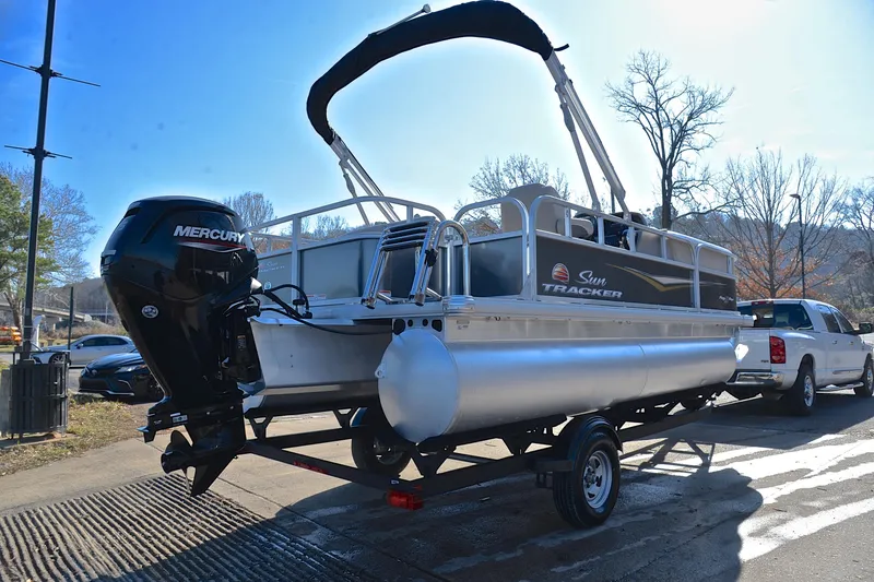 Slide: The Image of 2025 Sun Tracker Party Barge 18 DLX pontoon boat on trailer, parked outdoors. - 14