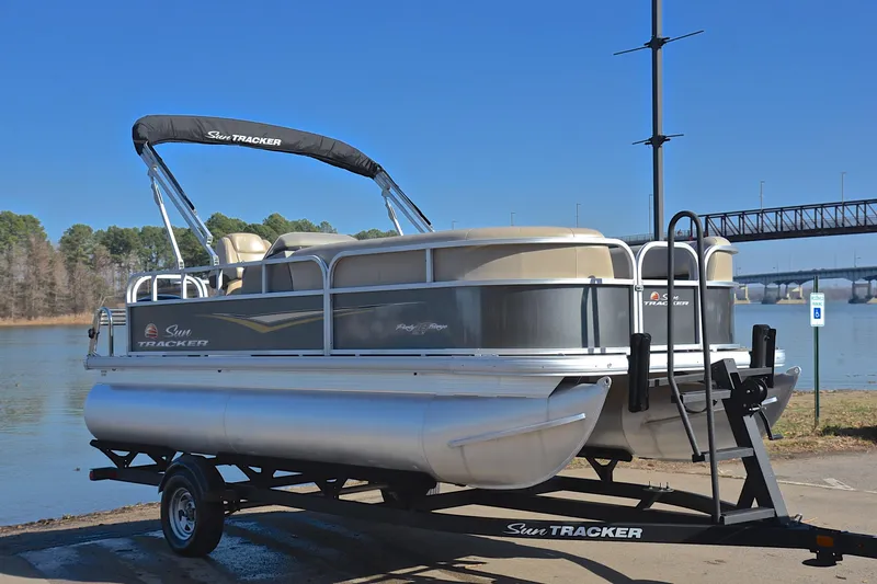 Slide: The Image of 2025 Sun Tracker Party Barge 18 DLX pontoon boat on trailer by a lake. - 16