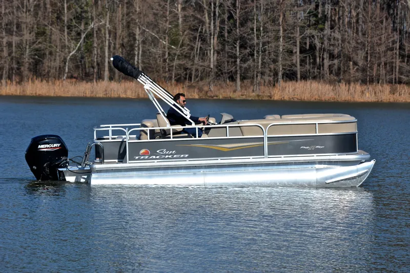 Slide: The Image of 2025 Sun Tracker Party Barge 18 DLX pontoon boat cruising on a serene lake. - 6