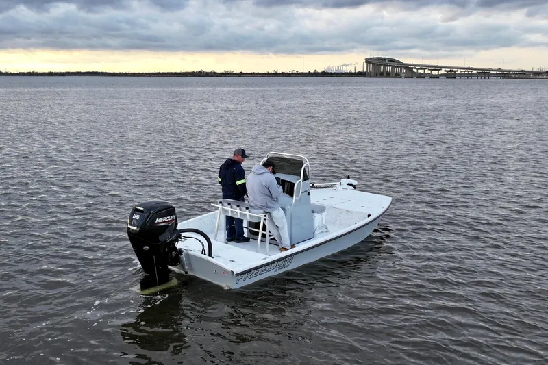 Slide: The Image of Freedom Boats 18' Patriot 2025 on calm water under cloudy sky. - 10