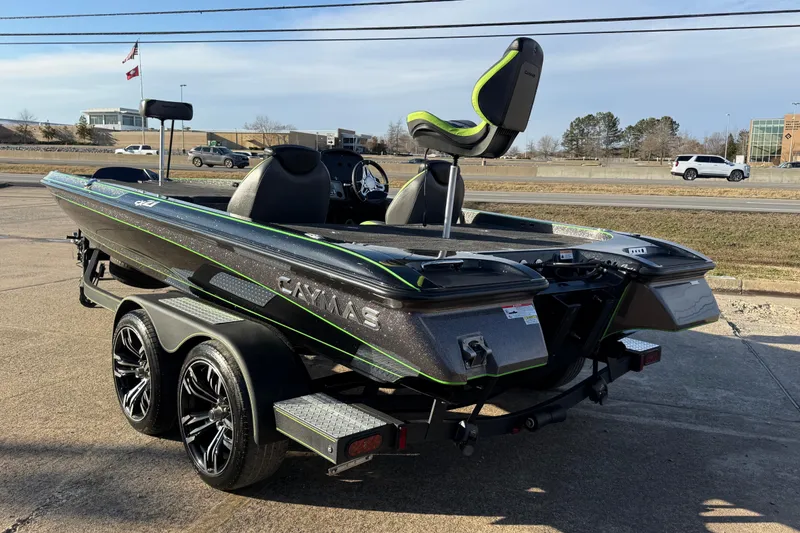Slide: The Image of 2021 Caymas CX 21 boat on trailer, sleek design with green accents, parked outdoors. - 2