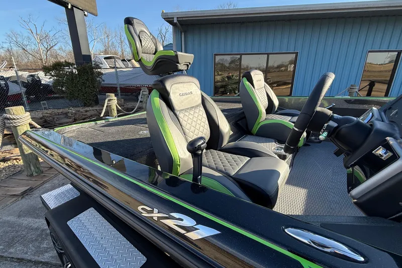 Slide: The Image of 2021 Caymas CX 21 boat interior with black and green seats, parked outdoors. - 9