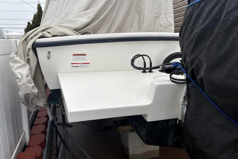 Slide: The Image of 2025 Dusky 227 boat with protective cover, rear view showing engine area. - 12