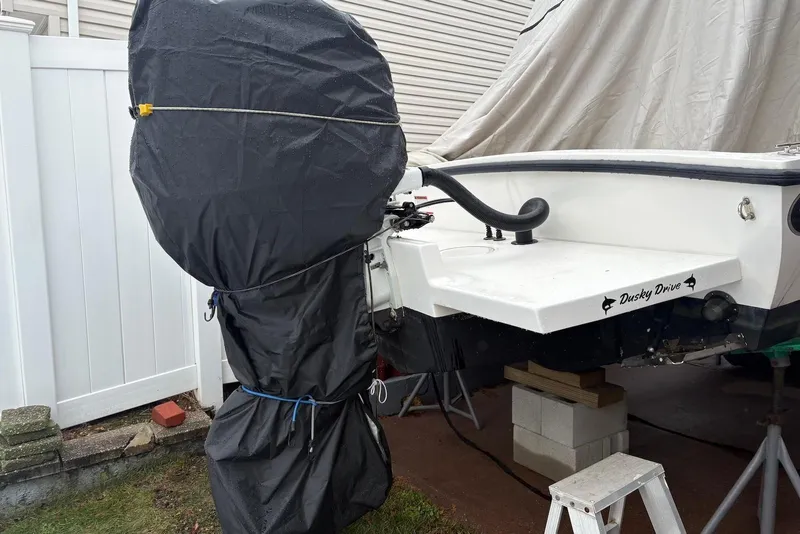 Slide: The Image of Covered outboard motor on a 2025 Dusky 227 boat, stored outdoors. - 14