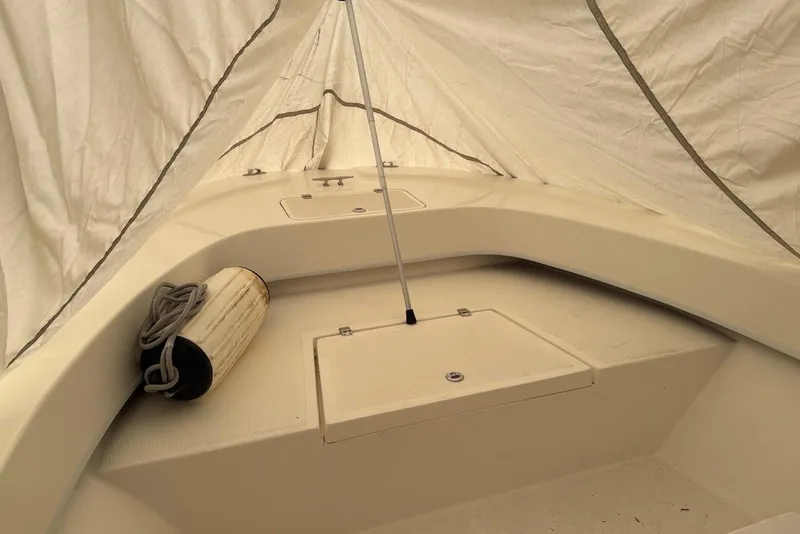 Slide: The Image of Dusky 227 boat interior, 2025 model, under protective cover with fender and rope. - 3