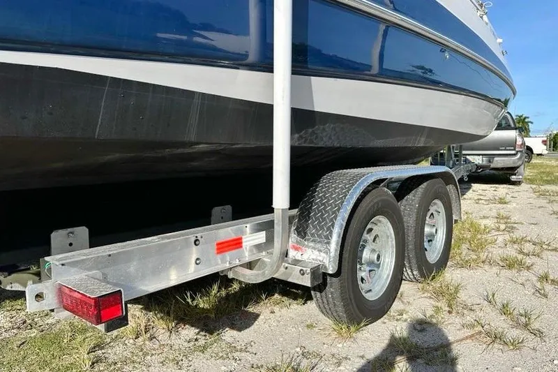 Slide: The Image of 2005 Four Winns 264 Funship boat on a dual-axle trailer, parked on grass. - 12