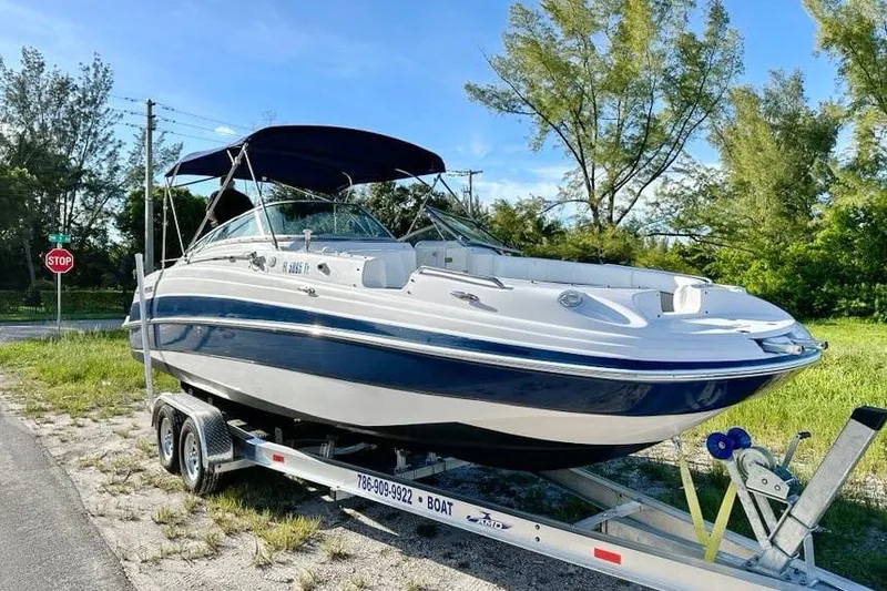 Slide: The Image of 2005 Four Winns 264 Funship boat on trailer, parked near greenery and stop sign. - 7