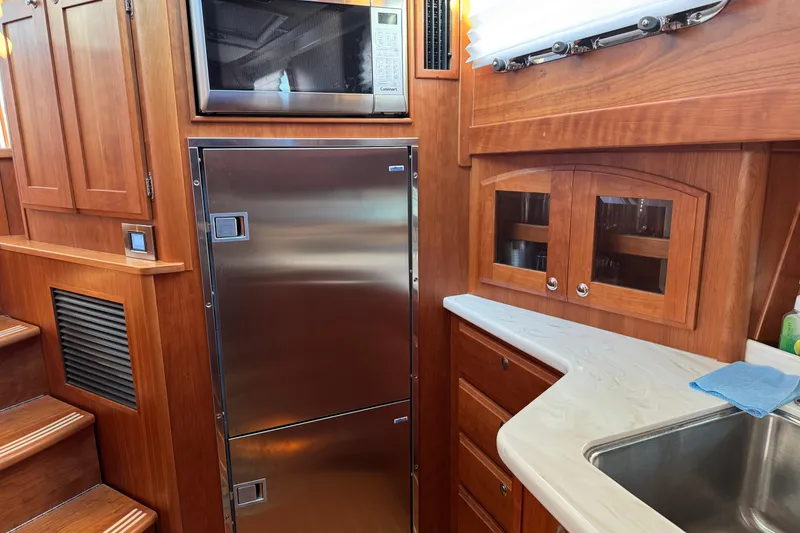 Slide: The Image of Interior of 2023 Sabre 48 Salon Express yacht kitchen with stainless appliances and wooden cabinetry. - 14