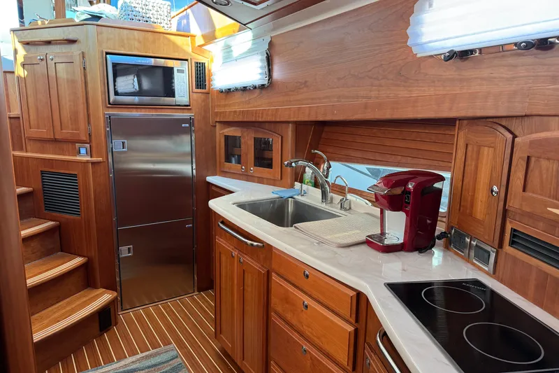 Slide: The Image of 2023 Sabre 48 Salon Express kitchen with wood cabinetry, stainless steel appliances, and modern fixtures. - 15