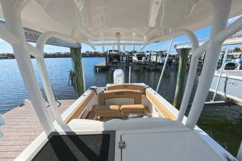 Slide: The Image of 2020 Velocity 262cc boat docked at marina, showcasing spacious seating and sleek design. - 10