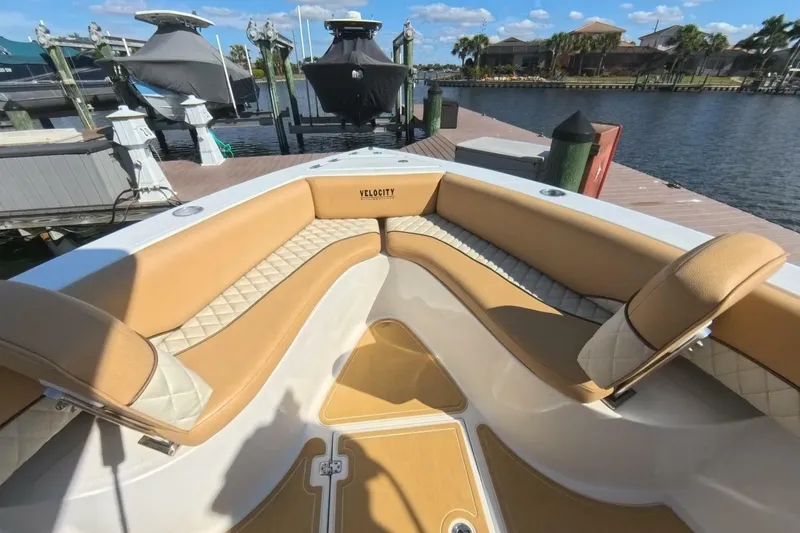 Slide: The Image of 2020 Velocity 262cc boat interior with tan seating at a marina dock. - 3