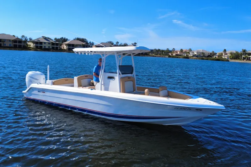 Slide: The Image of 2020 Velocity 262cc boat on calm water, clear sky, residential background. - 7