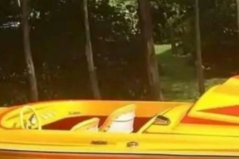 Slide: The Image of 2009 Sleekcraft Kuaui speedboat with vibrant orange and yellow design, parked outdoors. - 11