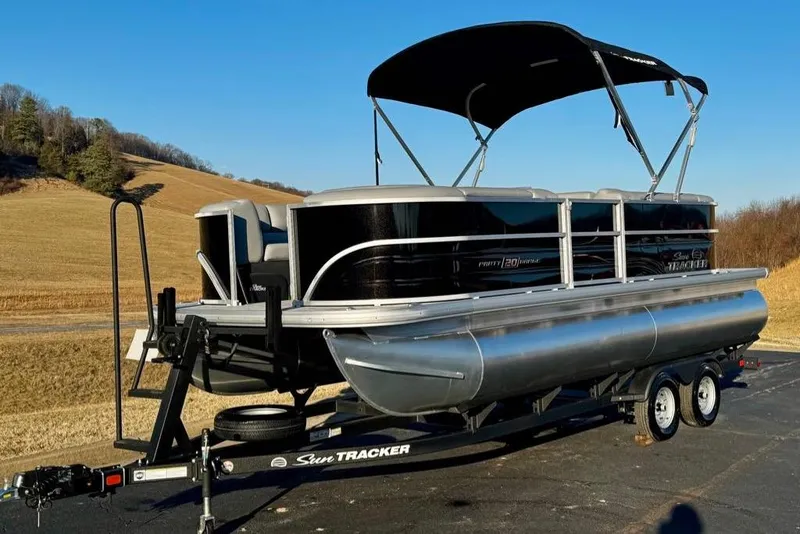 Slide: The Image of 2026 Sun Tracker Party Barge 20 DLX pontoon boat on trailer, scenic countryside background. - 2