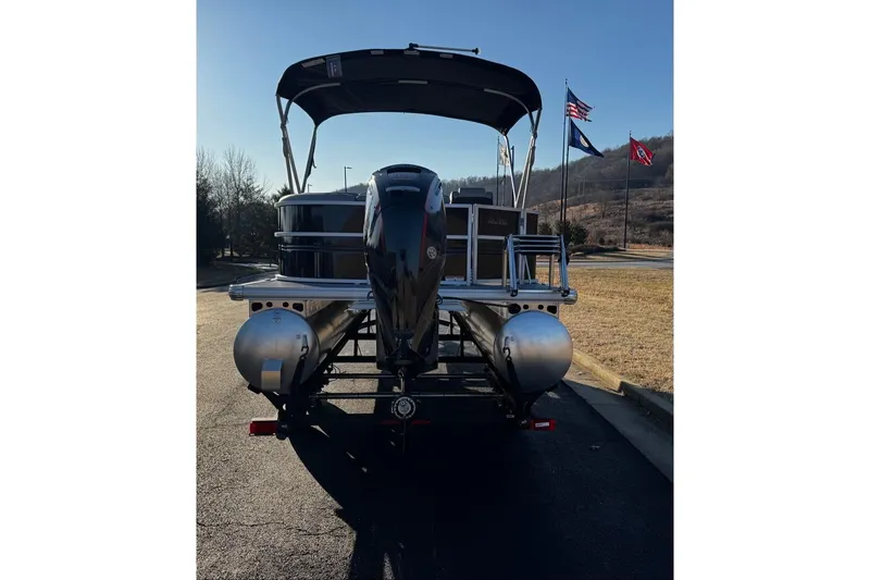 Slide: The Image of 2026 Sun Tracker Party Barge 20 DLX pontoon boat on trailer, flags in background. - 4