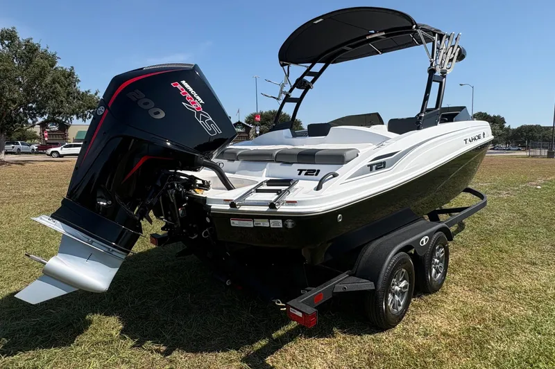 Slide: The Image of 2026 Tahoe T21 boat with a powerful outboard motor, parked on a trailer on grass. - 0
