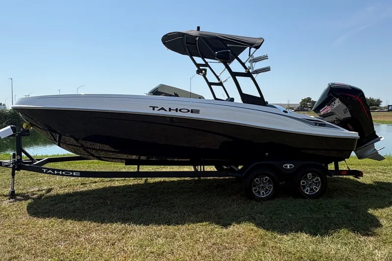 Slide: The Image of A black and white Tahoe T21 boat is on a trailer on grass. - 4