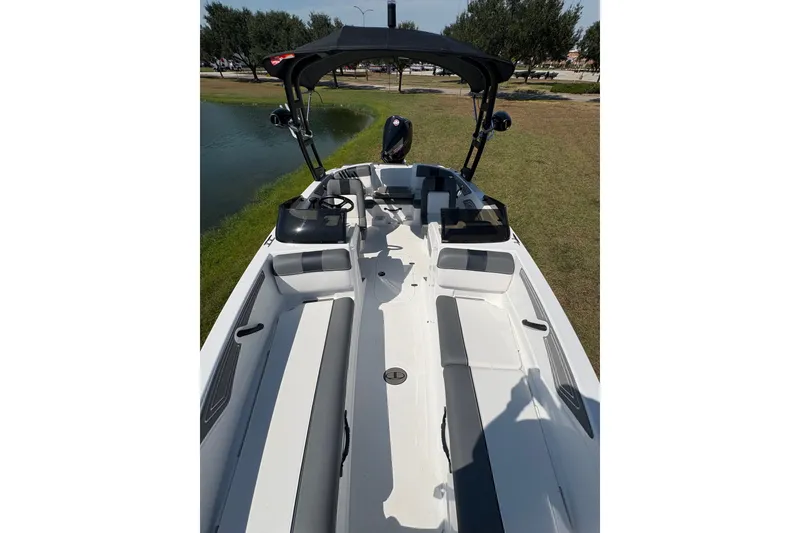 Slide: The Image of 2026 Tahoe T21 boat interior with seating, steering wheel, and canopy near a pond. - 8